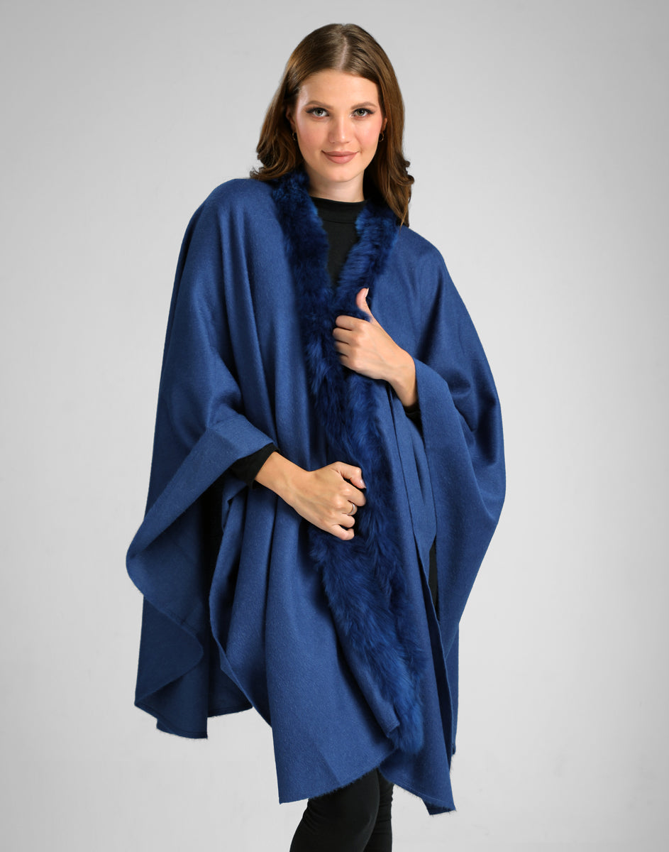 Modelo usando la ruana Front Fur color azul con borde de piel al frente, sobre fondo gris claro