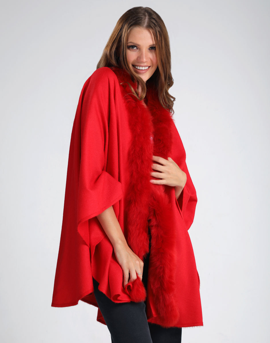 Modelo usando la ruana Front Fur color rojo con borde delantero de piel, en fondo neutro